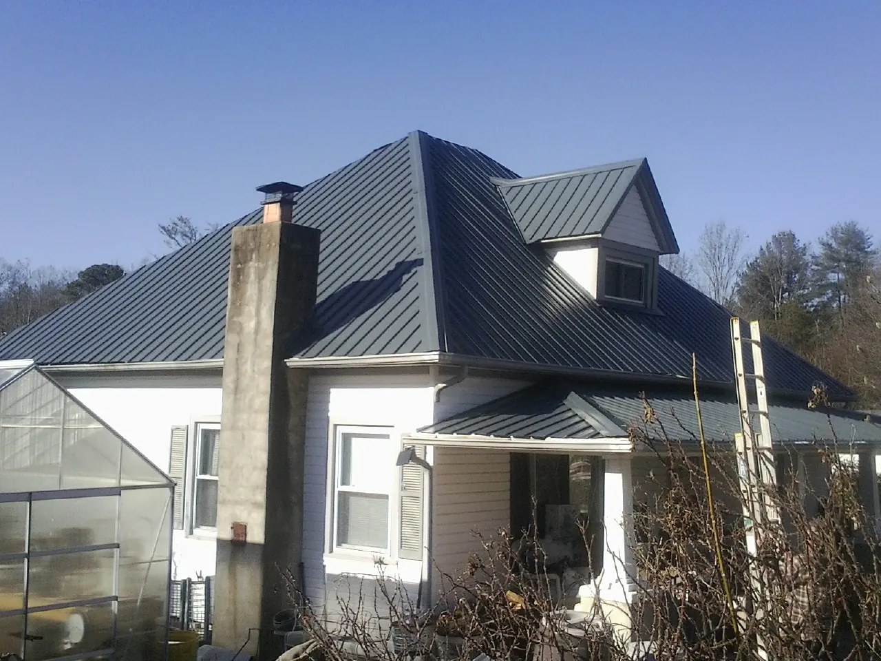 Dark blue standing seam metal roof on a white farmhouse with dormer — Slate & Tile Roof Repair by Roofing Brothers in Hiwassee