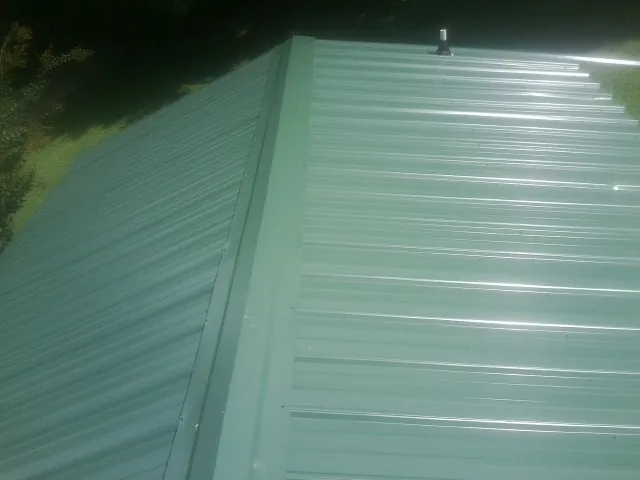 New green metal panels meeting at the ridge of a roof — Flat Roof Repair work by our crew in Hiwassee