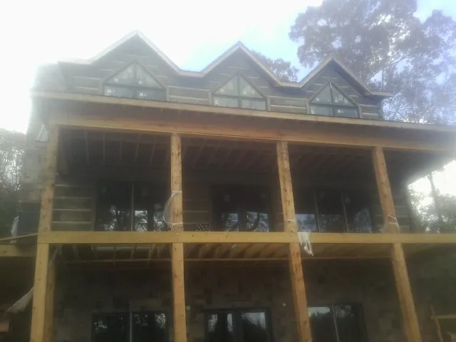 Dormers and porch framing on a large log home under construction — Roof Coating work by our crew in Hiwassee