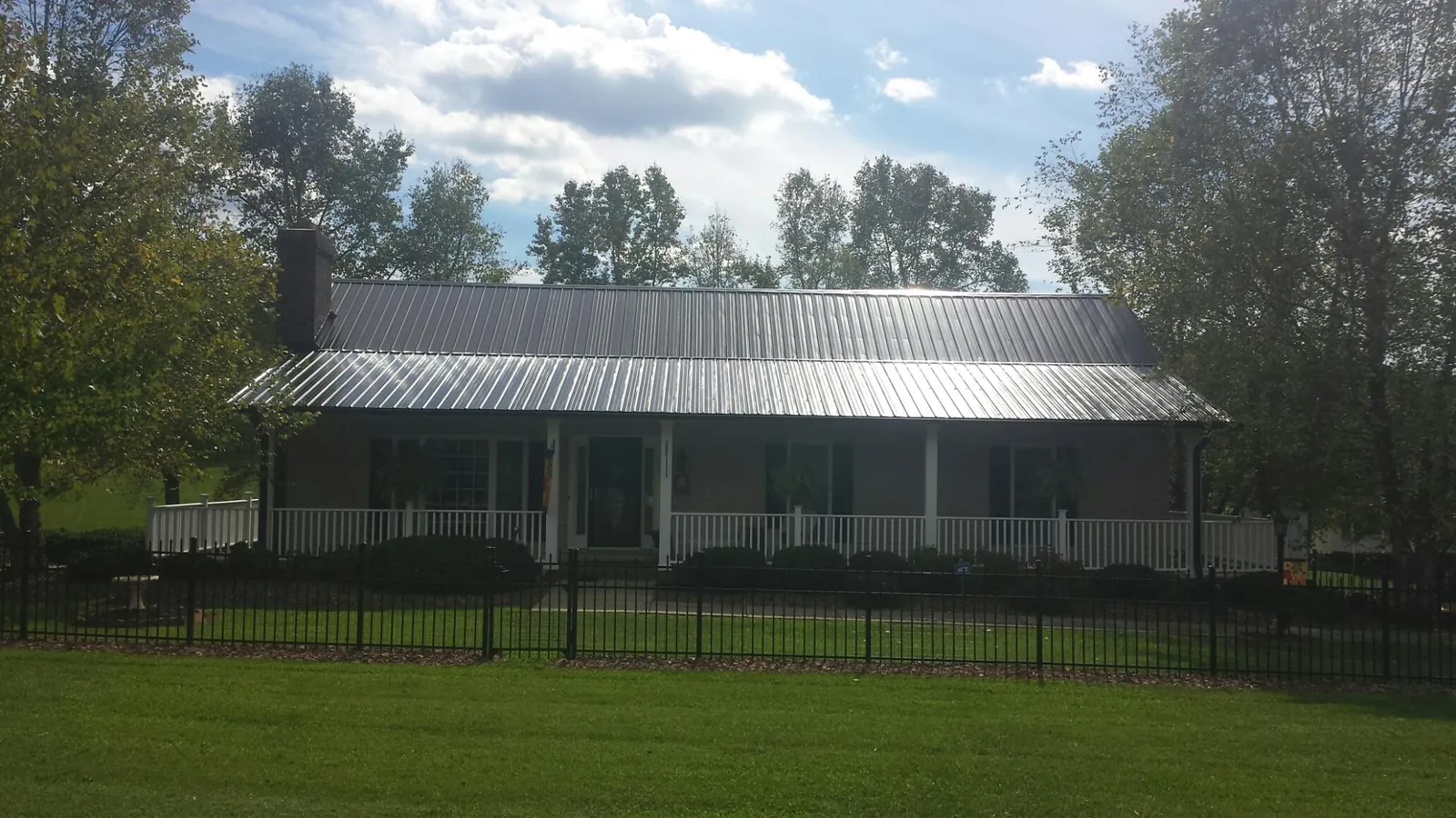 Gray metal roof on a brick ranch with a full width front porch — Gutter Guard Installation work by our crew in Hiwassee