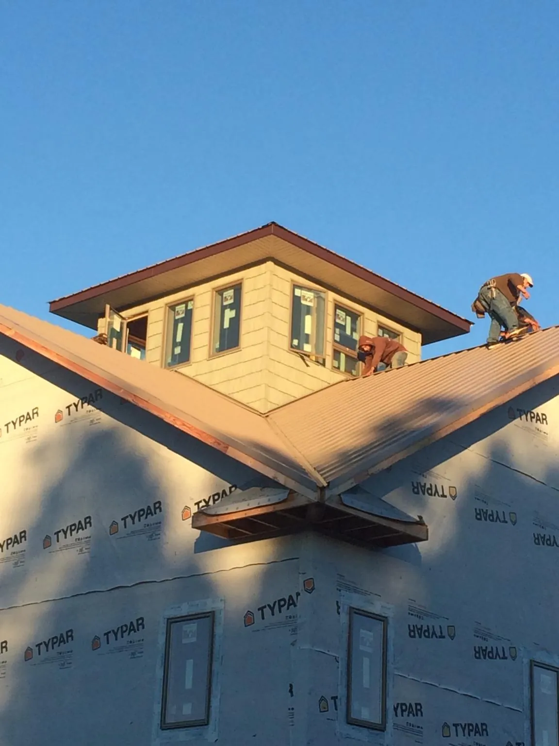 Roofers working around a rooftop cupola on a new metal roof at sunset — Roof Waterproofing in Hiwassee by Roofing Brothers